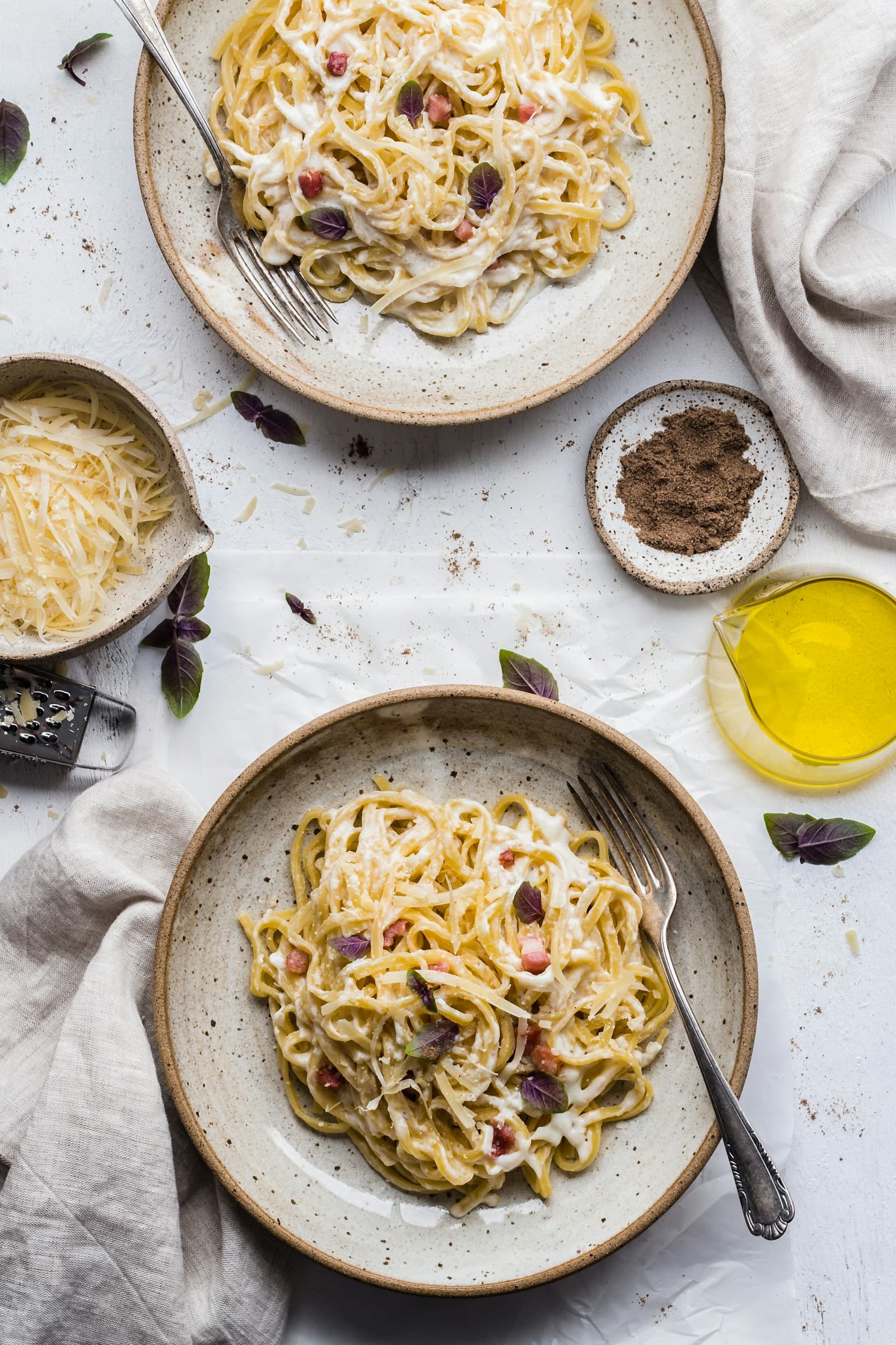 Creamy pasta with grated cheese and herbs beside olive oil and seasonings