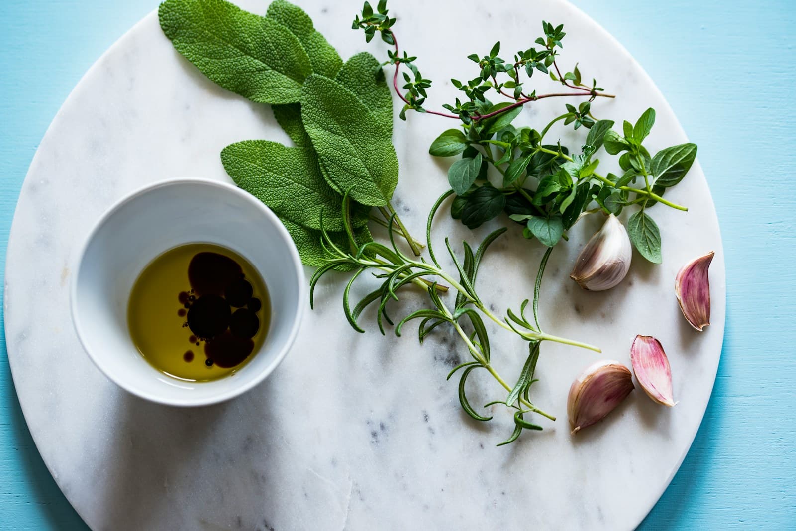 Olive oil and vinegar with garlic, sage, rosemary, thyme, and oregano on marble