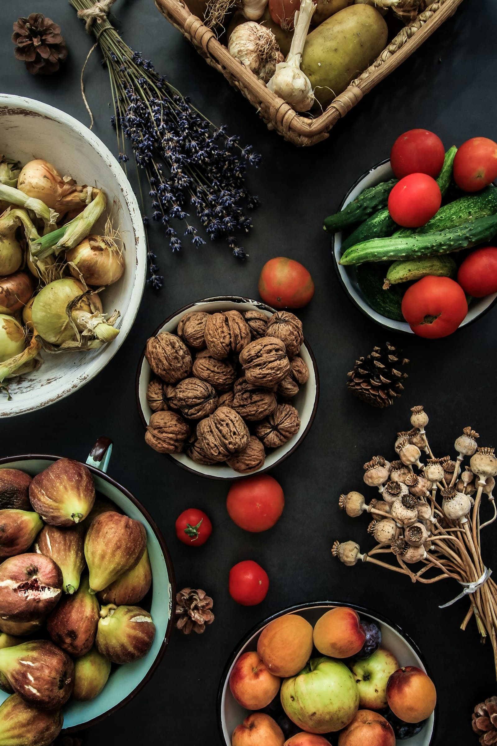 Walnuts, figs, tomatoes, onions, garlic, cucumbers, and other produce on a dark table