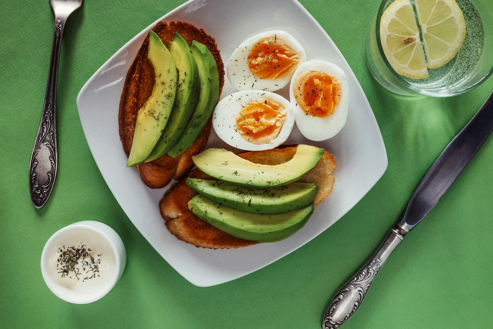 Avocado toast with halved boiled eggs on a white plate